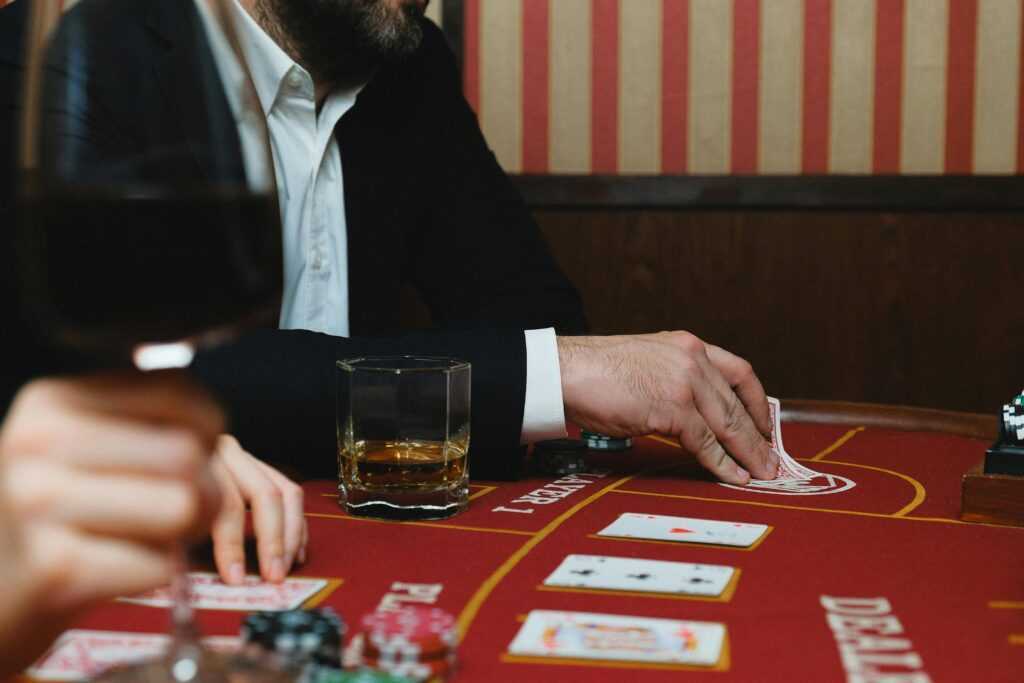 Elegant casino scene with playing cards, poker chips, and beverages on a table.